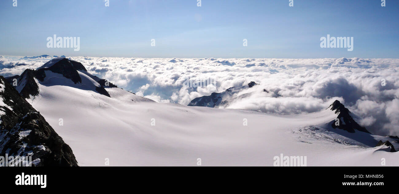 Panorama blick auf eine Berglandschaft in der Schweiz mit einem großen Gletscher und ein Meer von Wolken unter Stockfoto