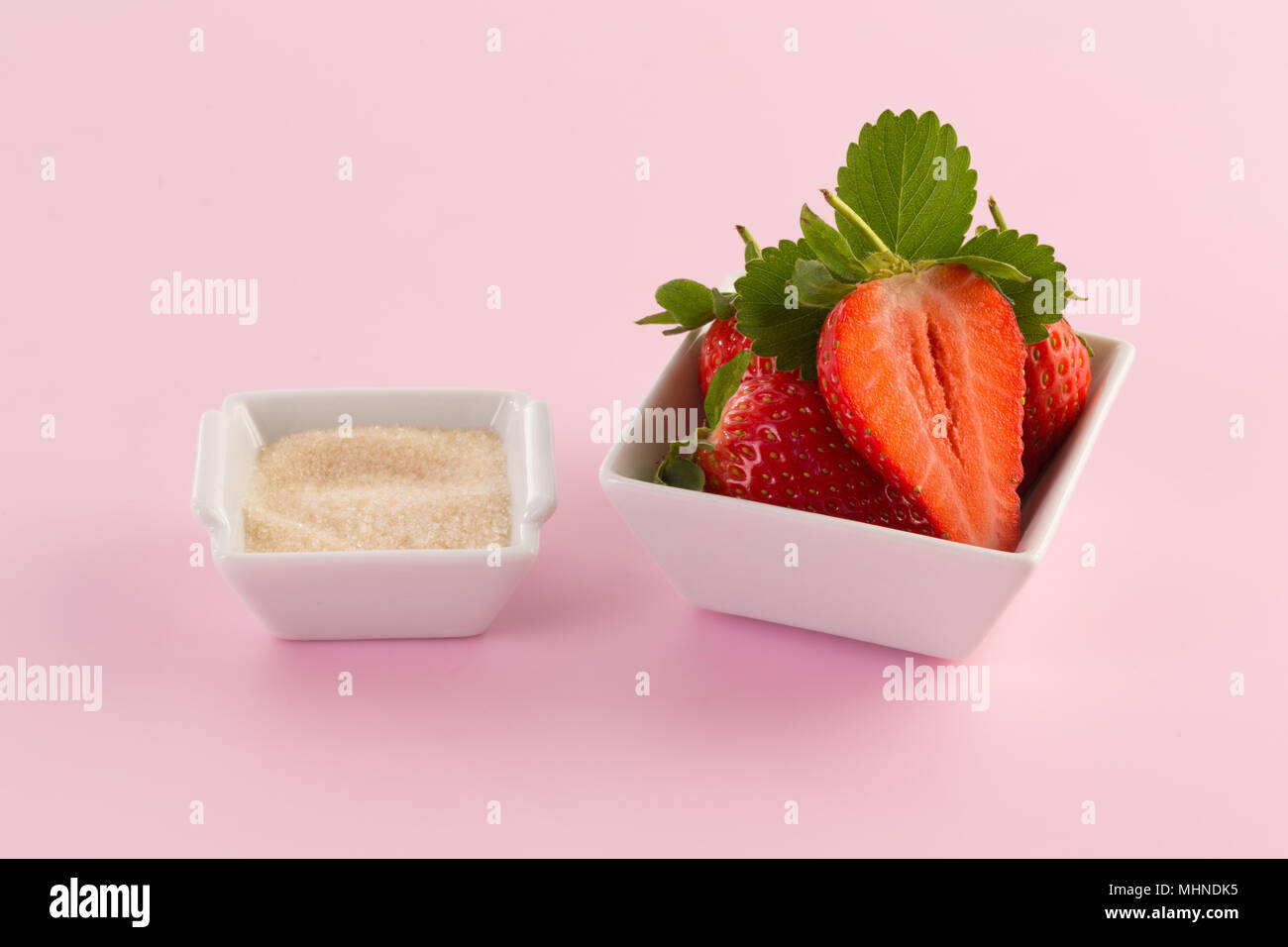 Frische Erdbeeren und Zucker auf einem rosa Hintergrund Stockfoto