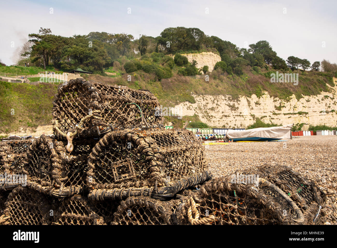 Leere crab Töpfe stapelten sich auf einem Kieselstrand mit zurück Tropfen Kreidefelsen, Bier, Devon, Großbritannien. Stockfoto