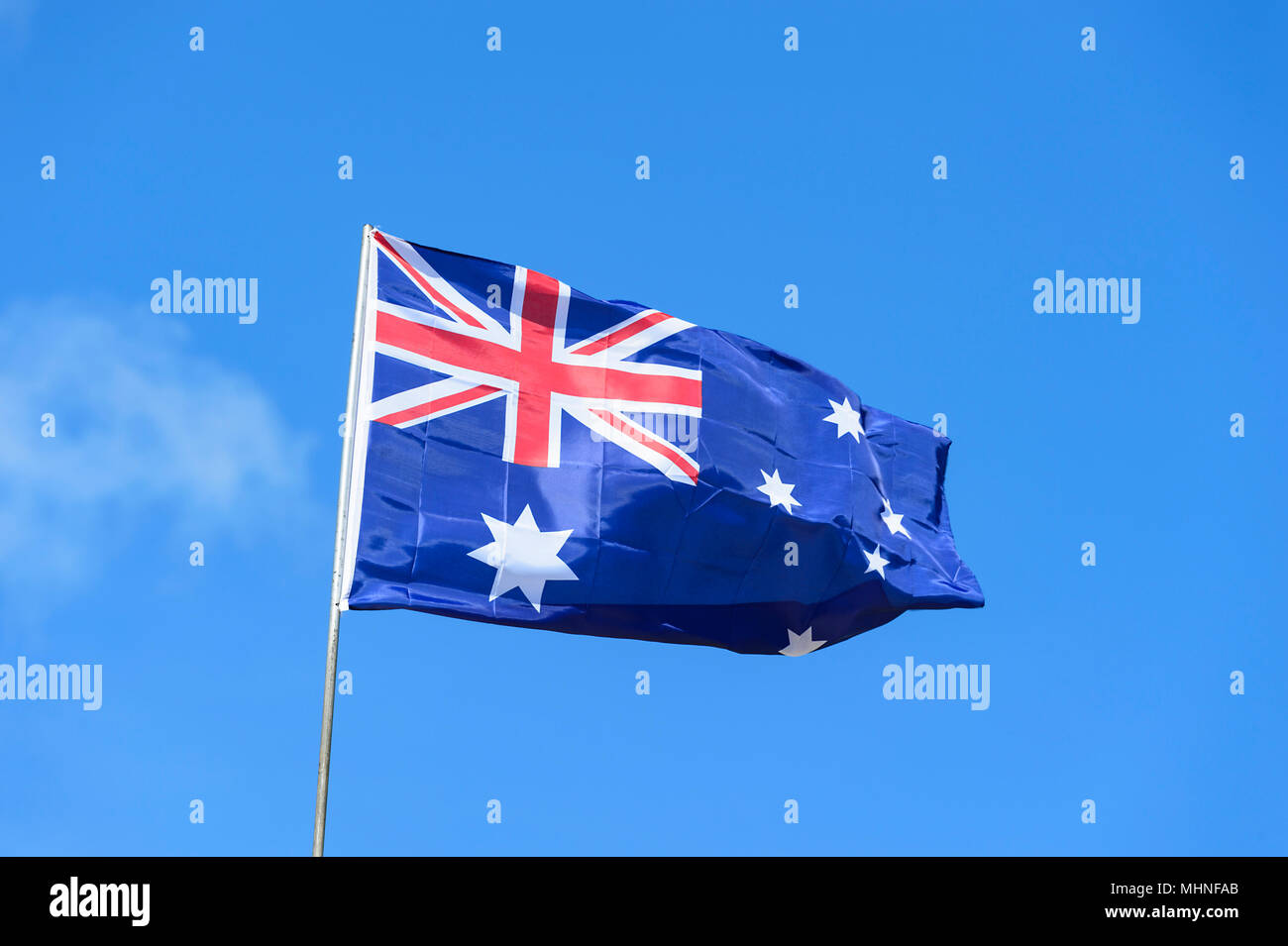 Australische Flagge vor blauem Himmel fließt Stockfoto