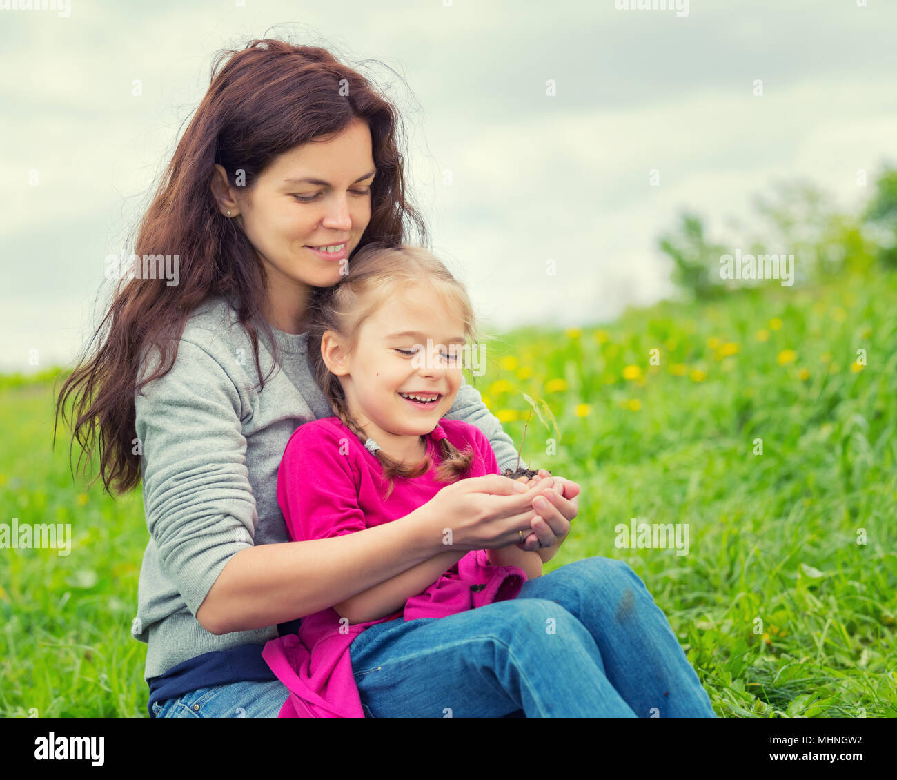Mutter und Tochter, die kleine grüne Pflanze in den Händen halten Stockfoto