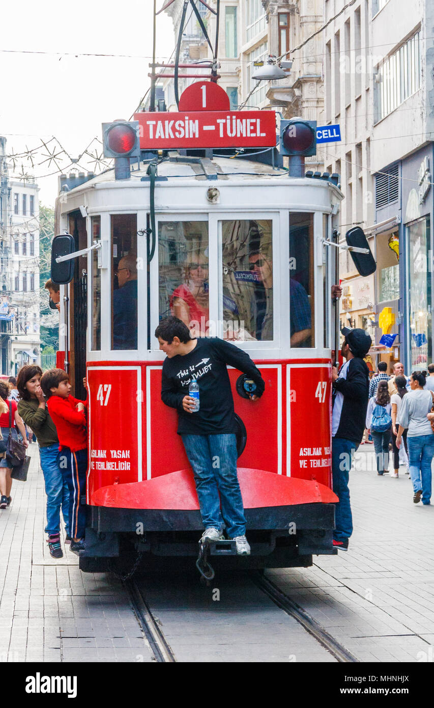 Istanbul, Türkei - 8. Oktober 2011: Kinder als Trittbrettfahrer auf Retro Straßenbahn auf der Istiklal Caddesi. Die Straßenbahn fährt zum Taksim-platz. Stockfoto