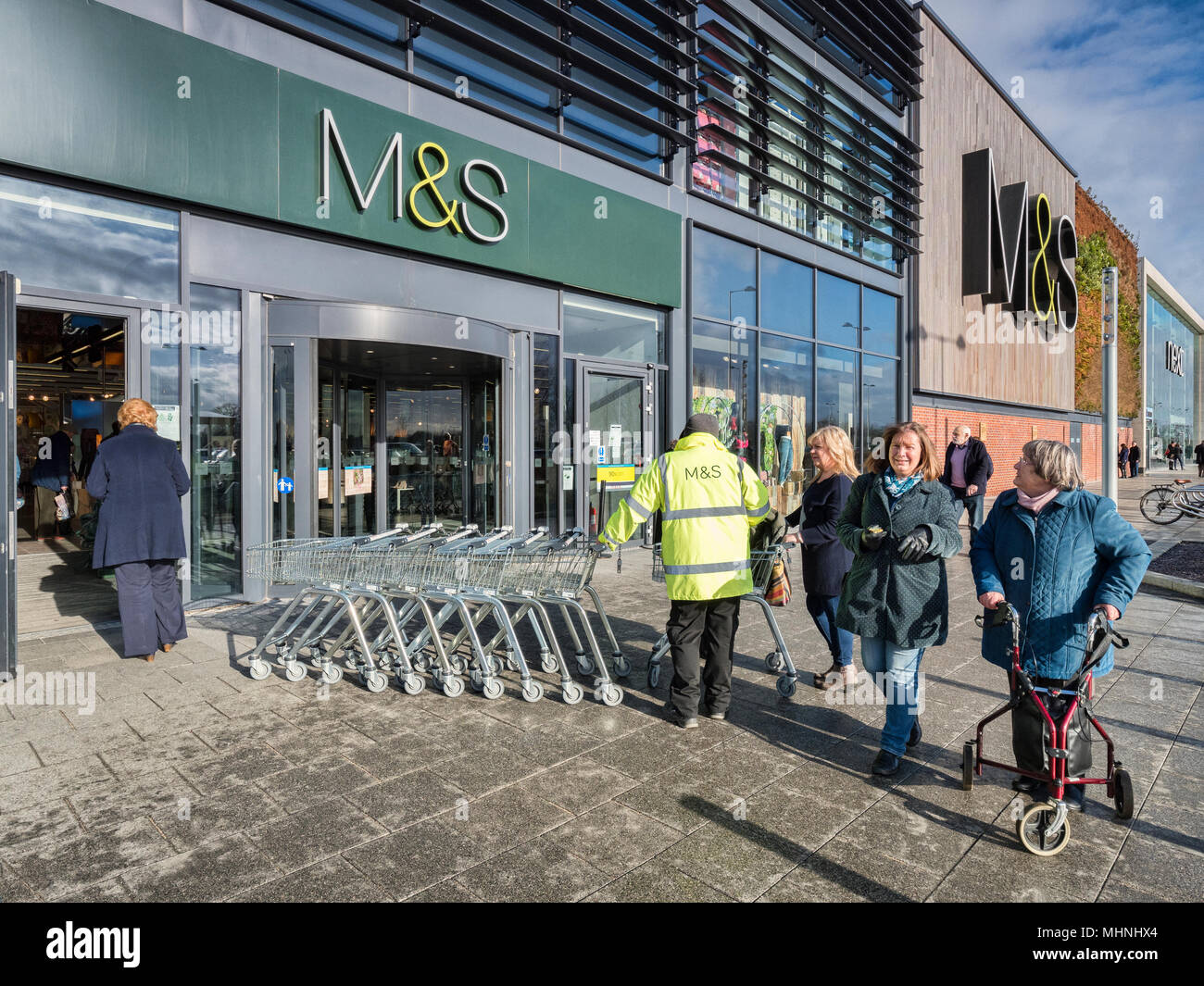 2. Februar 2018: York, UK-eine M&S-Mitarbeiter in einer hohen vis Weste, außerhalb des Speichers in der Vangarde Einkaufszentrum, Mönche Kreuz arbeiten, und weibliche sho Stockfoto