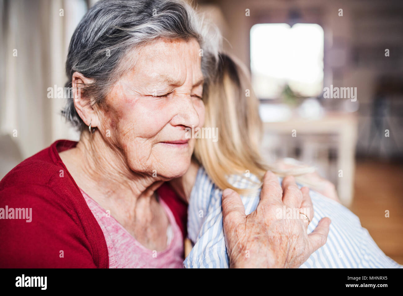 Eine alte Oma mit einem erwachsenen Enkelin zu Hause, umarmen sich. Stockfoto