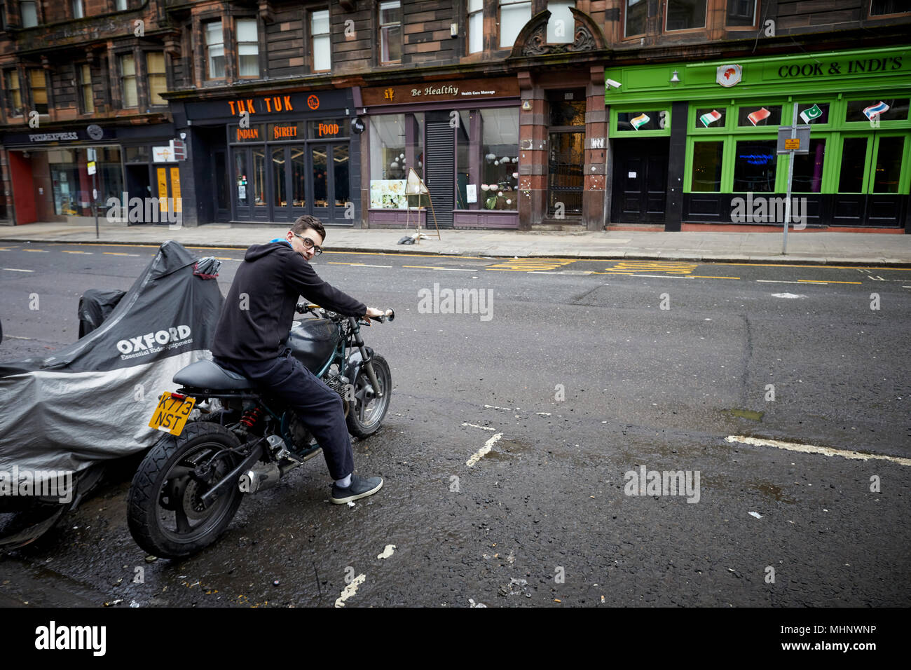 Glasgow in Schottland, der Sauchiehall Street junge Bewohner seine Motorrad starten Stockfoto