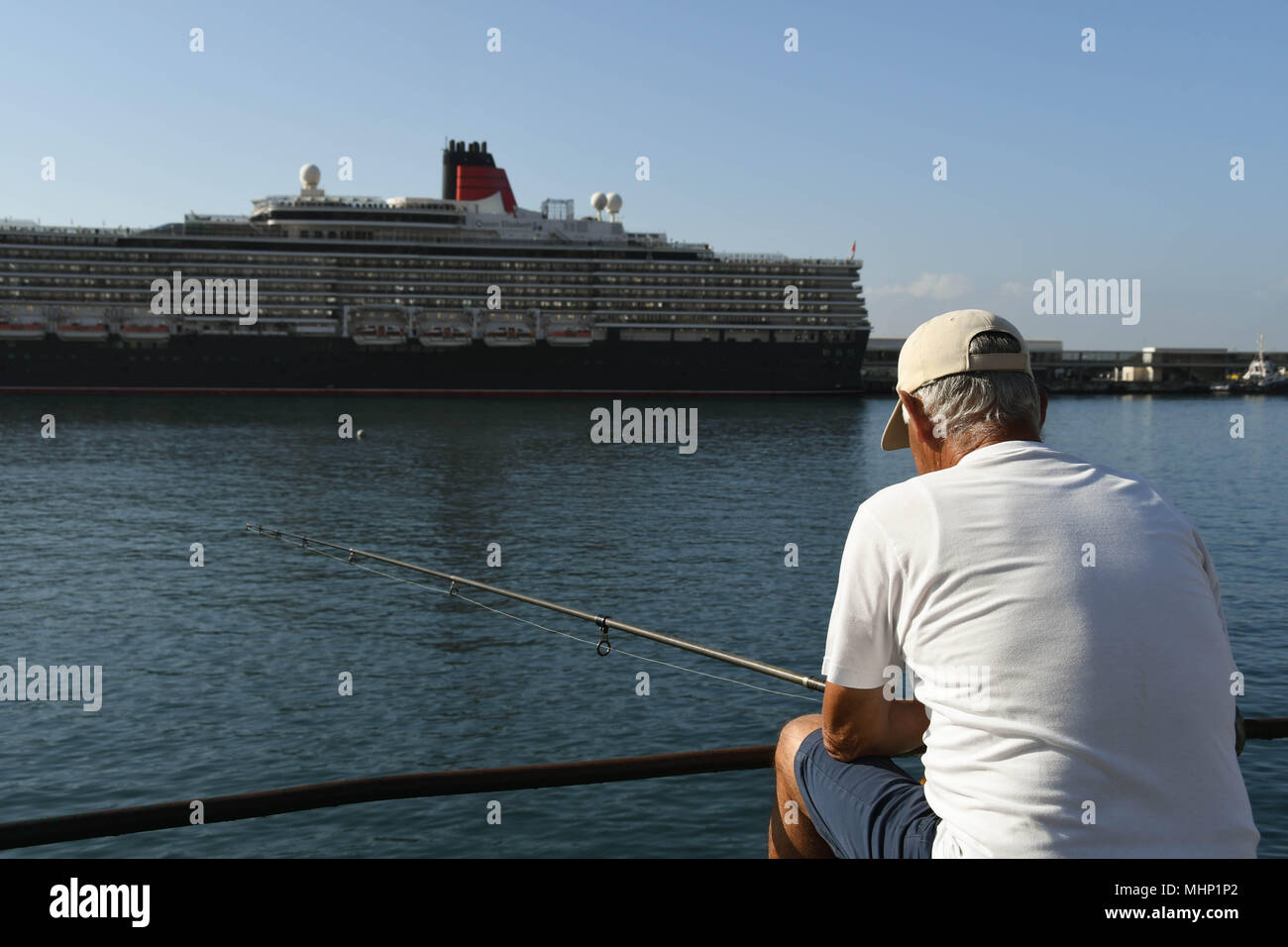 Person angeln von der Hafenseite in Funchal, Madeira. Das kreuzfahrtschiff Queen Elizabeth ist im Hintergrund Stockfoto