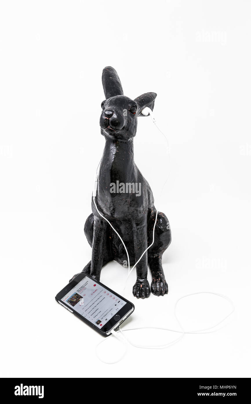 Schwarz lackiert Messing Modell einer Hase mit iphone und earpods. Stockfoto