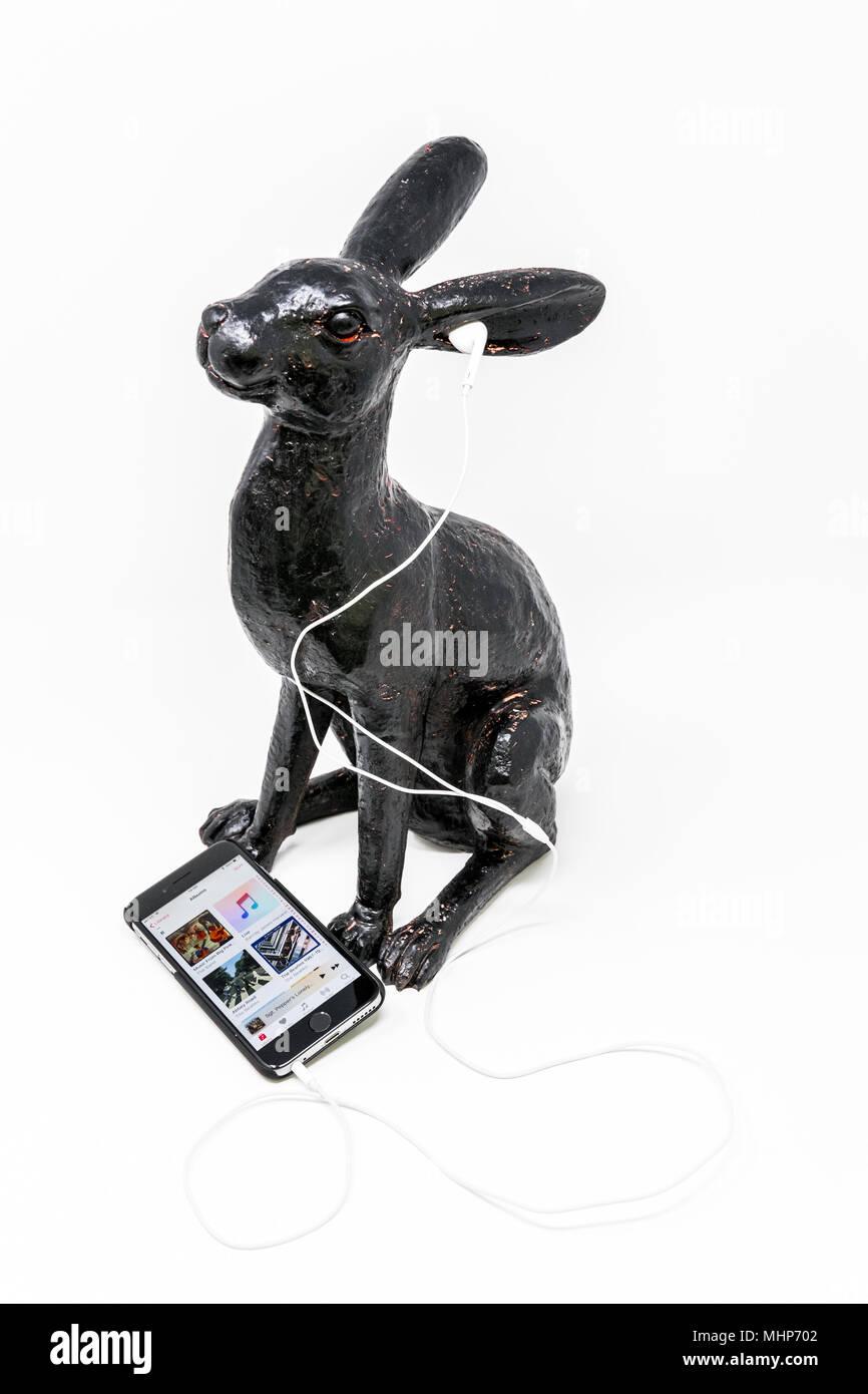 Schwarz lackiert Messing Modell einer Hase mit iphone und earpods. Stockfoto