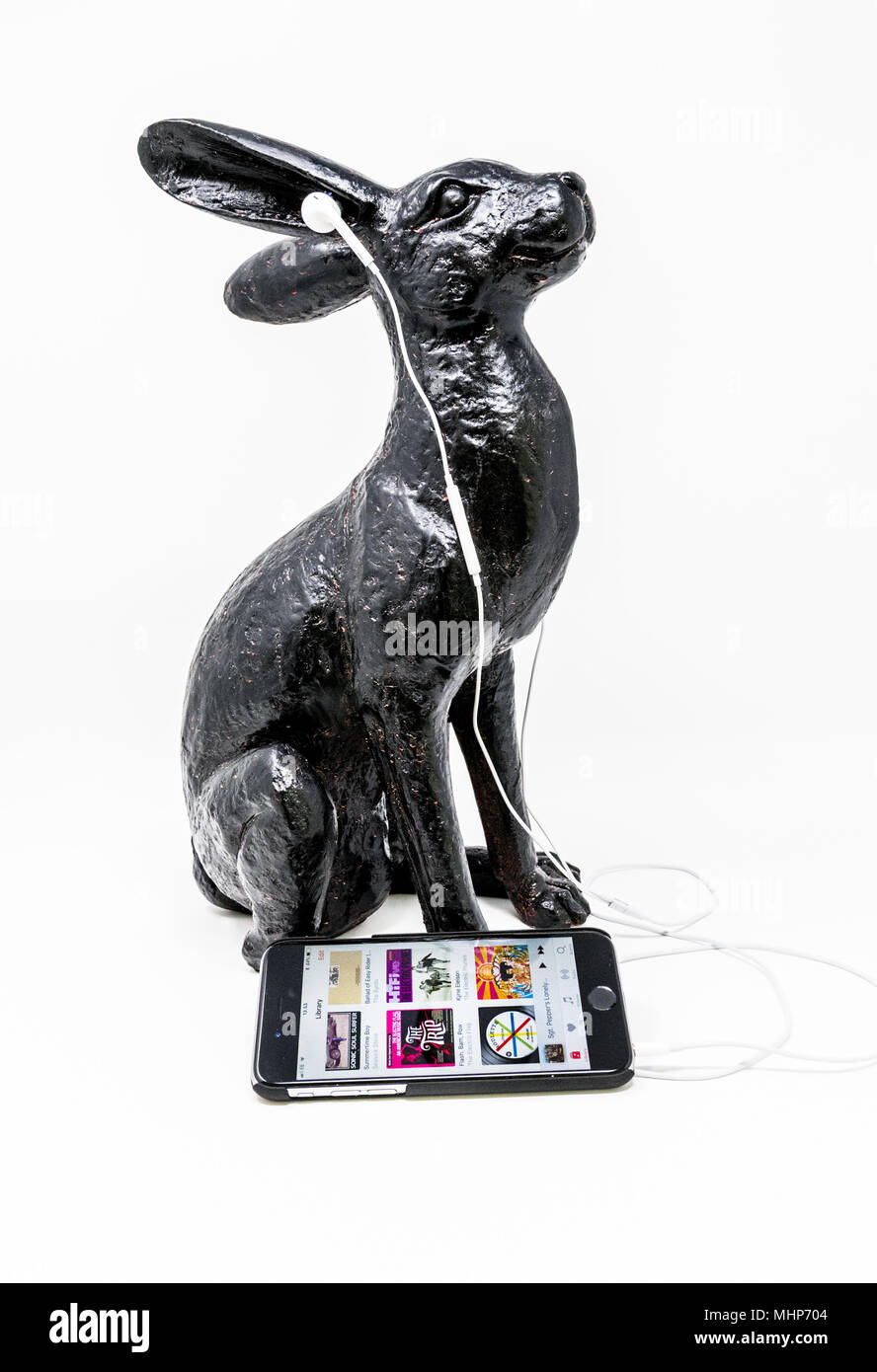 Schwarz lackiert Messing Modell einer Hase mit iphone und earpods. Stockfoto