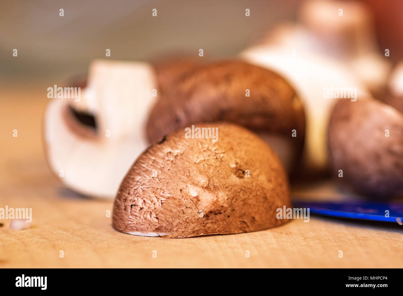 In Scheiben geschnittenen Champignons auf Holz Schneidebrett, blau Messerklinge. Stockfoto