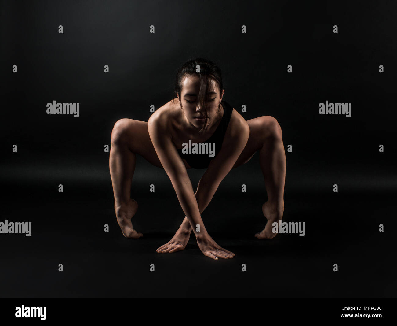 Sportlich fit darkhair Frau in Schwarz Sportbekleidung im Studio mit schwarzem Hintergrund. Tanzen, Streching, Pilates, Yoga und Fitness stellt Stockfoto