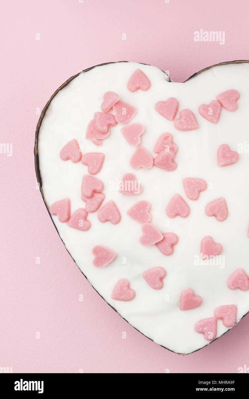 Weißen herzförmigen Muffin mit wenig Zucker Herzen Rosa auf rosa Hintergrund eingerichtet. Bild vertikal. Stockfoto