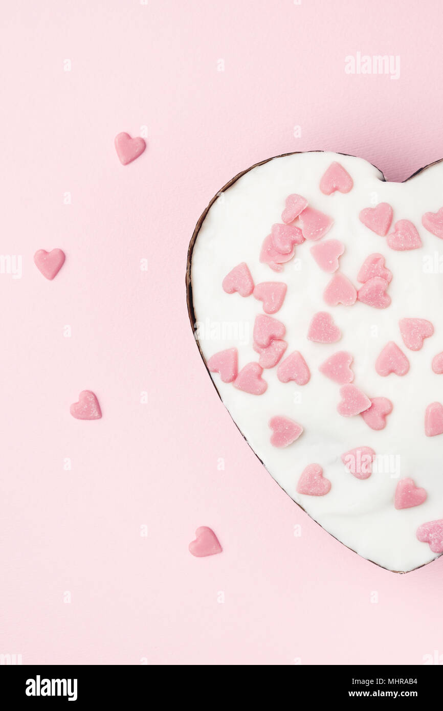 Weißen herzförmigen Muffin mit wenig Zucker Herzen Rosa auf rosa Hintergrund eingerichtet. Bild vertikal. Stockfoto