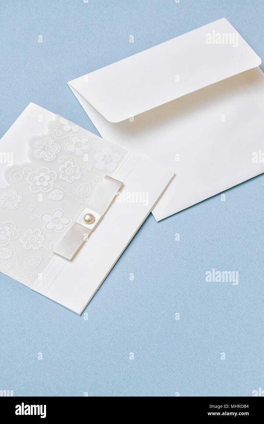 Weiß hochzeit einladung mit Blumen spitze Abbildung und White Ribbon auf hellblauem Papier Hintergrund. Vertikale erschossen. Süße und schöne Elemente. Stockfoto