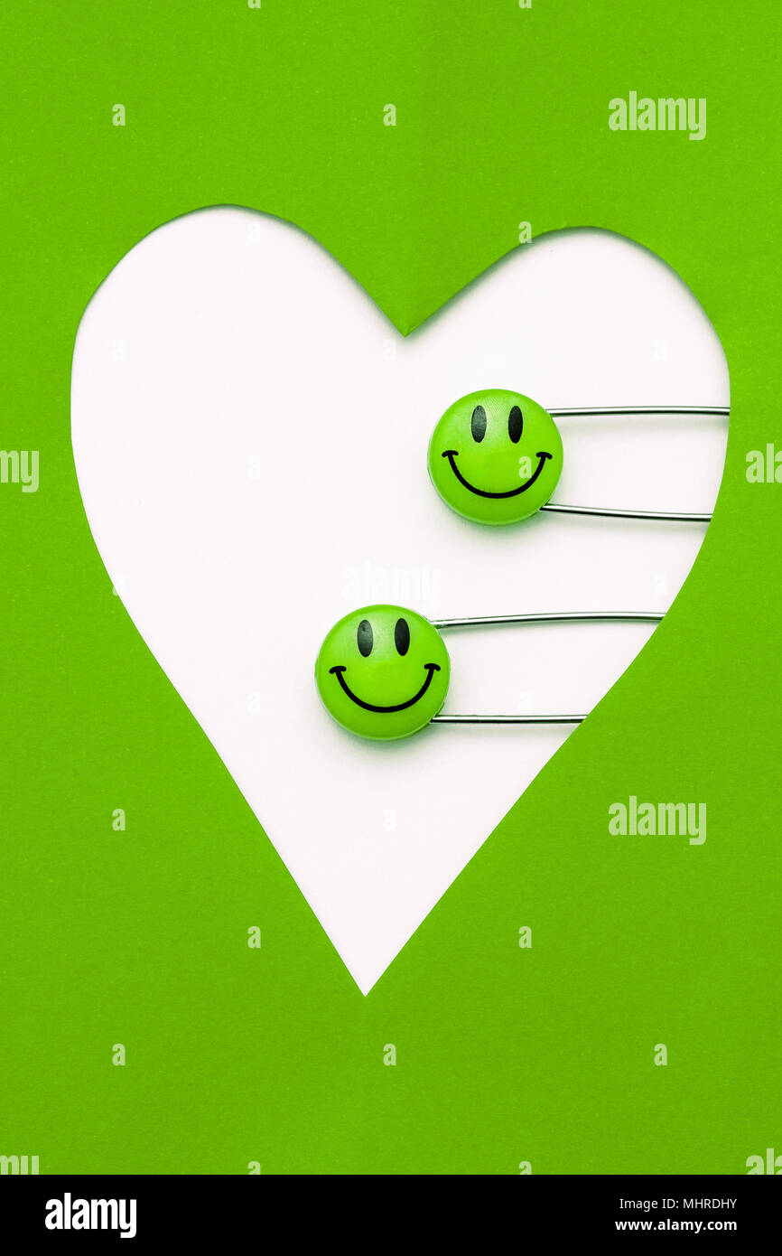 Kunststoff Kopf metall Sicherheitsnadeln in Herzform Papier festgesteckt. Frisches Grün Lächeln emoticon Safety Pin. Nett und lustig bunte Emoticons. Stockfoto
