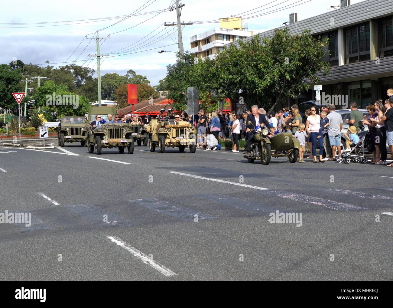 Menschenmassen jubeln Veteran Army Men März in vintage Armee Fahrzeuge in Coffs Harbour ANZAC Day Parade in Australien Stockfoto