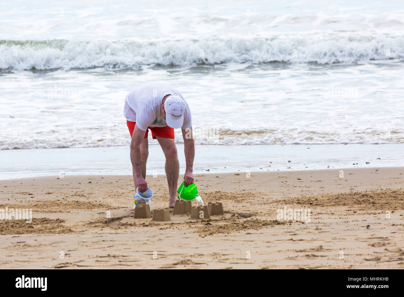 Bournemouth, Dorset, Großbritannien. 3. Mai 2018. UK Wetter: sonnig Nachmittag am Bournemouth Strände cool, wie Besucher die Sonne am Meer genießen. Älterer Mann gießt Wasser aus Eimern in Graben um Sandburgen am Strand. Credit: Carolyn Jenkins/Alamy leben Nachrichten Stockfoto