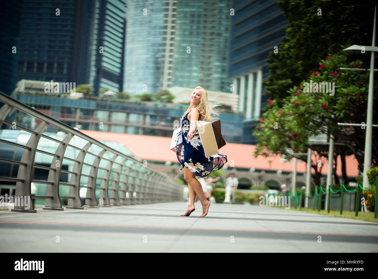 Die Freude an der... Aufgeregt, schöne Frau legere blaues Kleid mit Blumen, Einkaufstaschen in den Straßen mit Wolkenkratzern Stockfoto