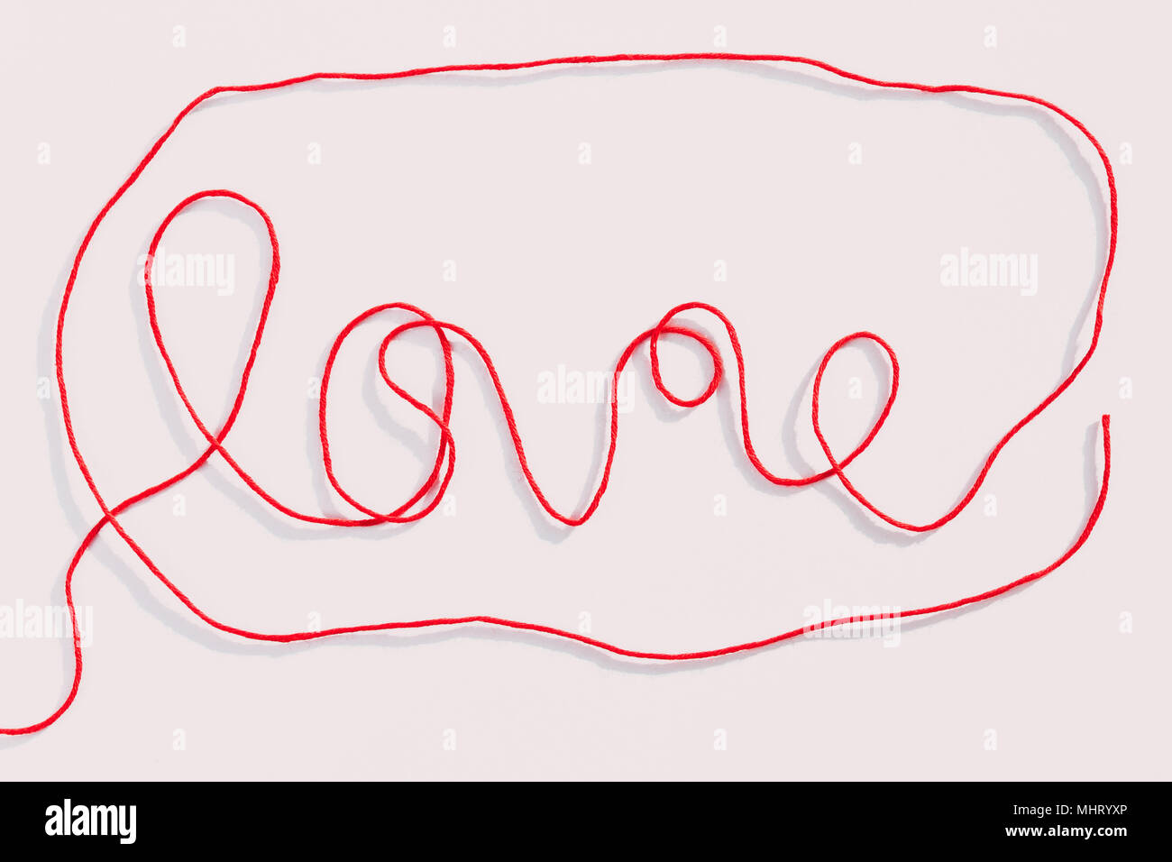 Wort Liebe mit roten Wollfäden auf weißem Hintergrund geschrieben. Horizontale Ansicht. Stockfoto