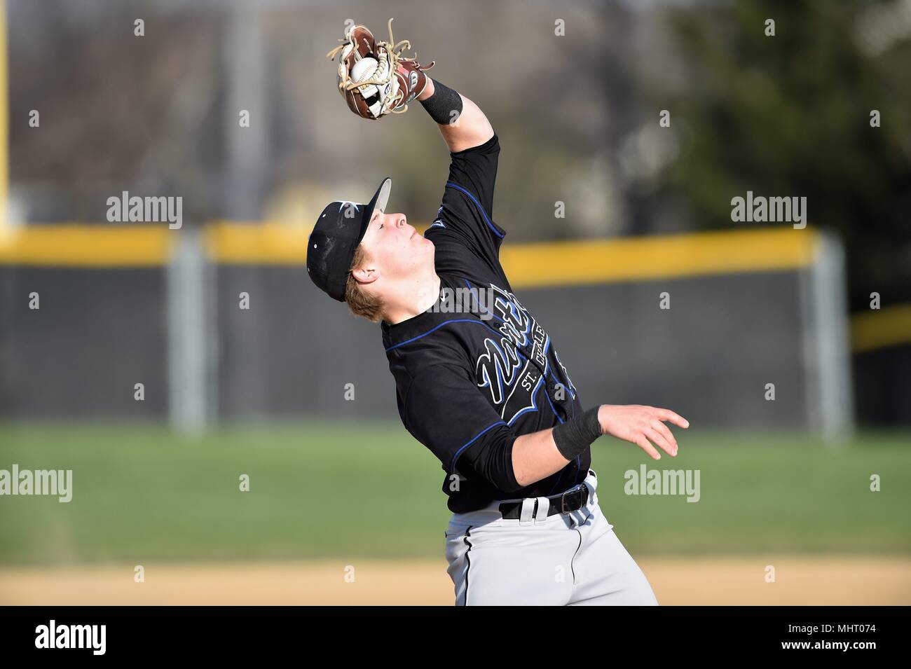 Dritter Basisspieler Kämpfen der Wind, wie er sich ein Pop Up auf dem infield Fänge. USA. Stockfoto