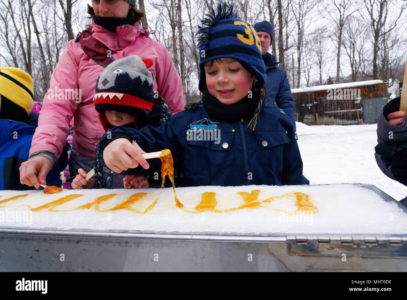 Kinder essen Ahornsirup taffy auf Eis zu einem Sugar shack in Québec, Kanada gegossen Stockfoto