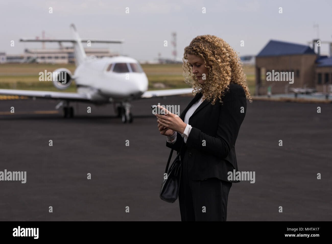Geschäftsfrau mit Handy an Anschlußklemme Stockfoto