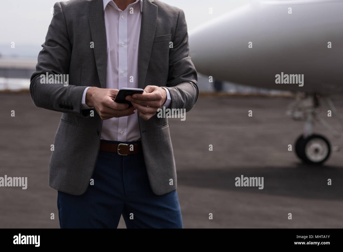 Geschäftsmann mit Mobiltelefon an Anschlußklemme Stockfoto