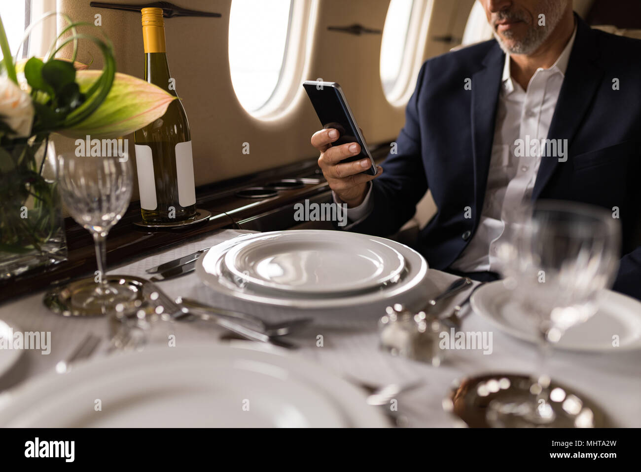Geschäftsmann mit Mobiltelefon in Private Jet Stockfoto