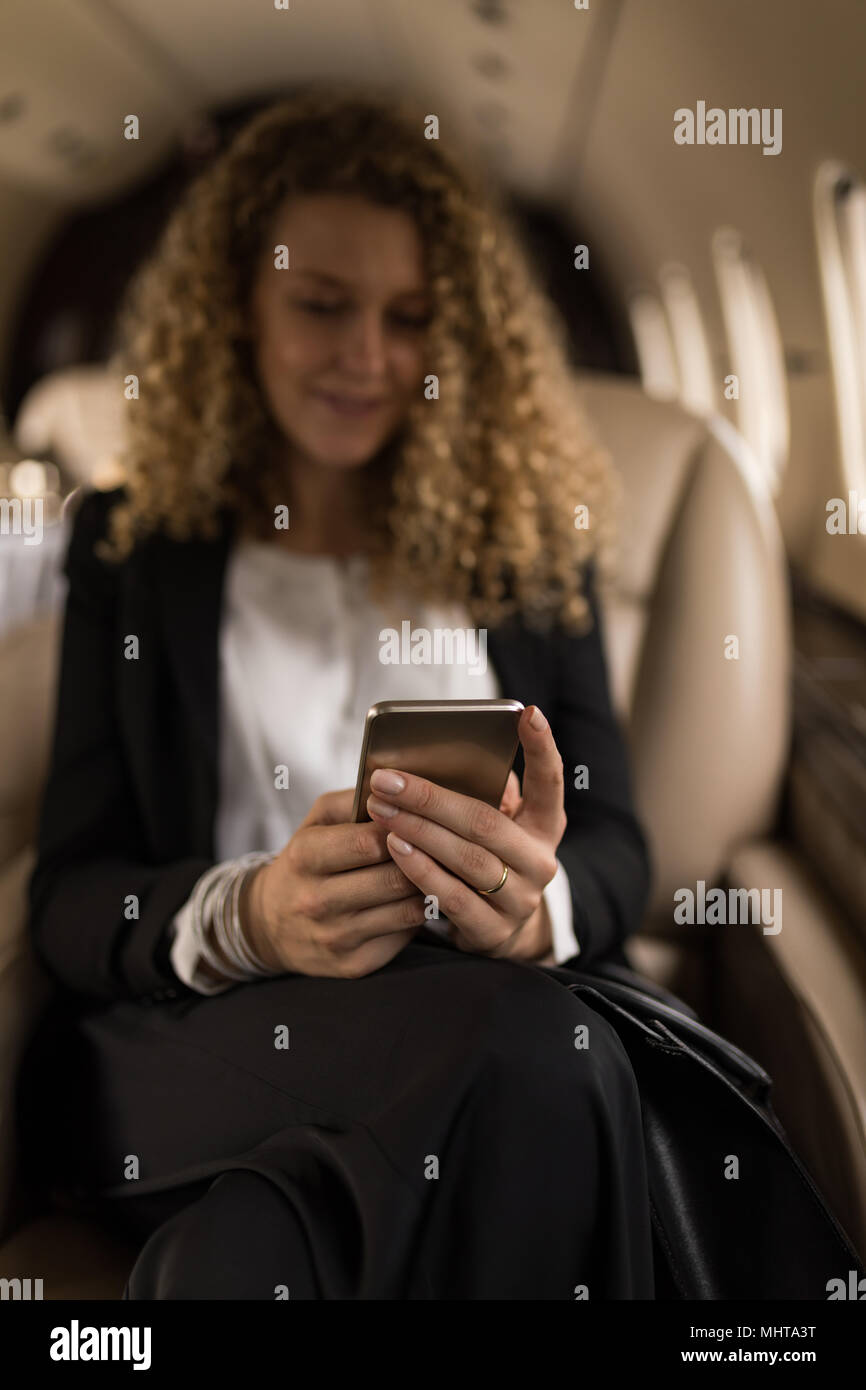 Geschäftsfrau mit Handy in Private Jet Stockfoto