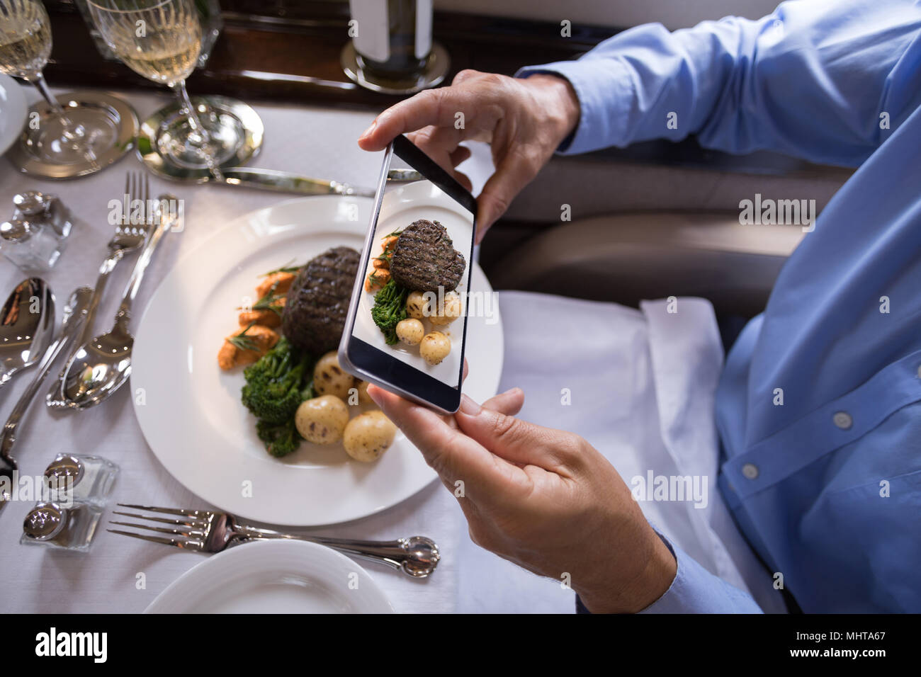 Geschäftsmann unter Foto von Essen mit Handy in Private Jet Stockfoto