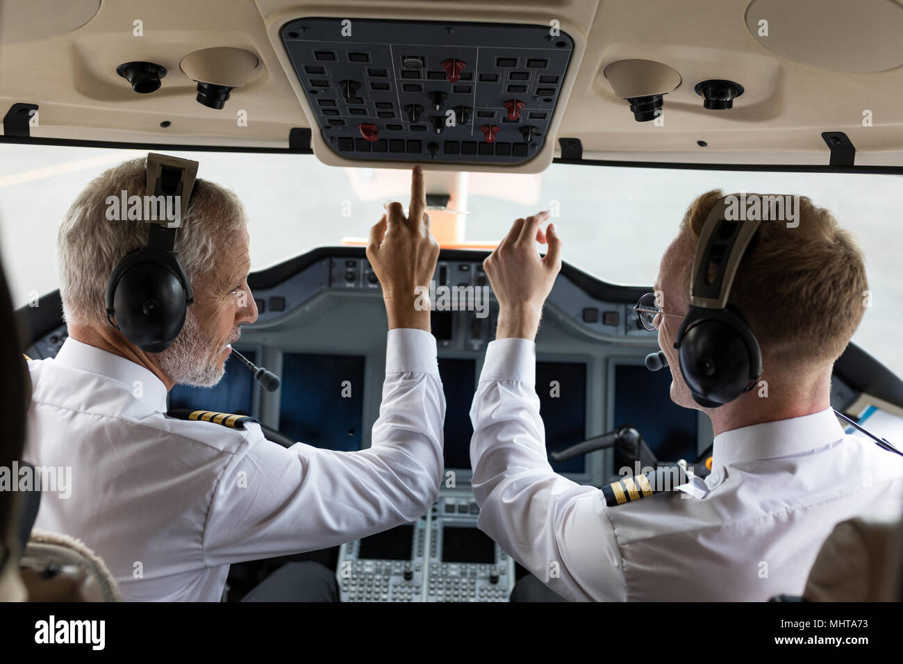 Zwei männliche Piloten Drücken der Taste im Cockpit Stockfoto