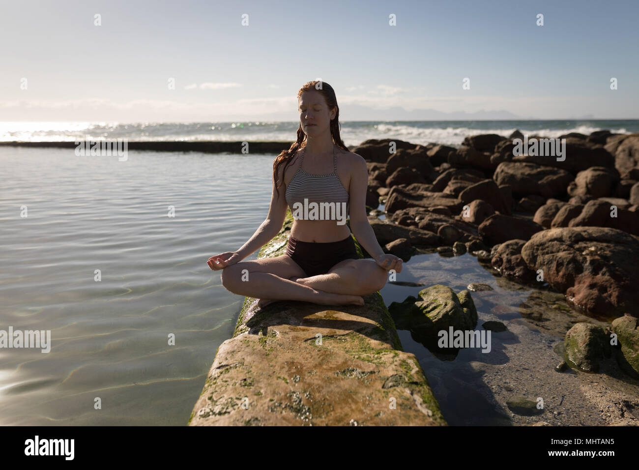 Attraktive Frau die Meditation in der Nähe von Beachside pool Stockfoto