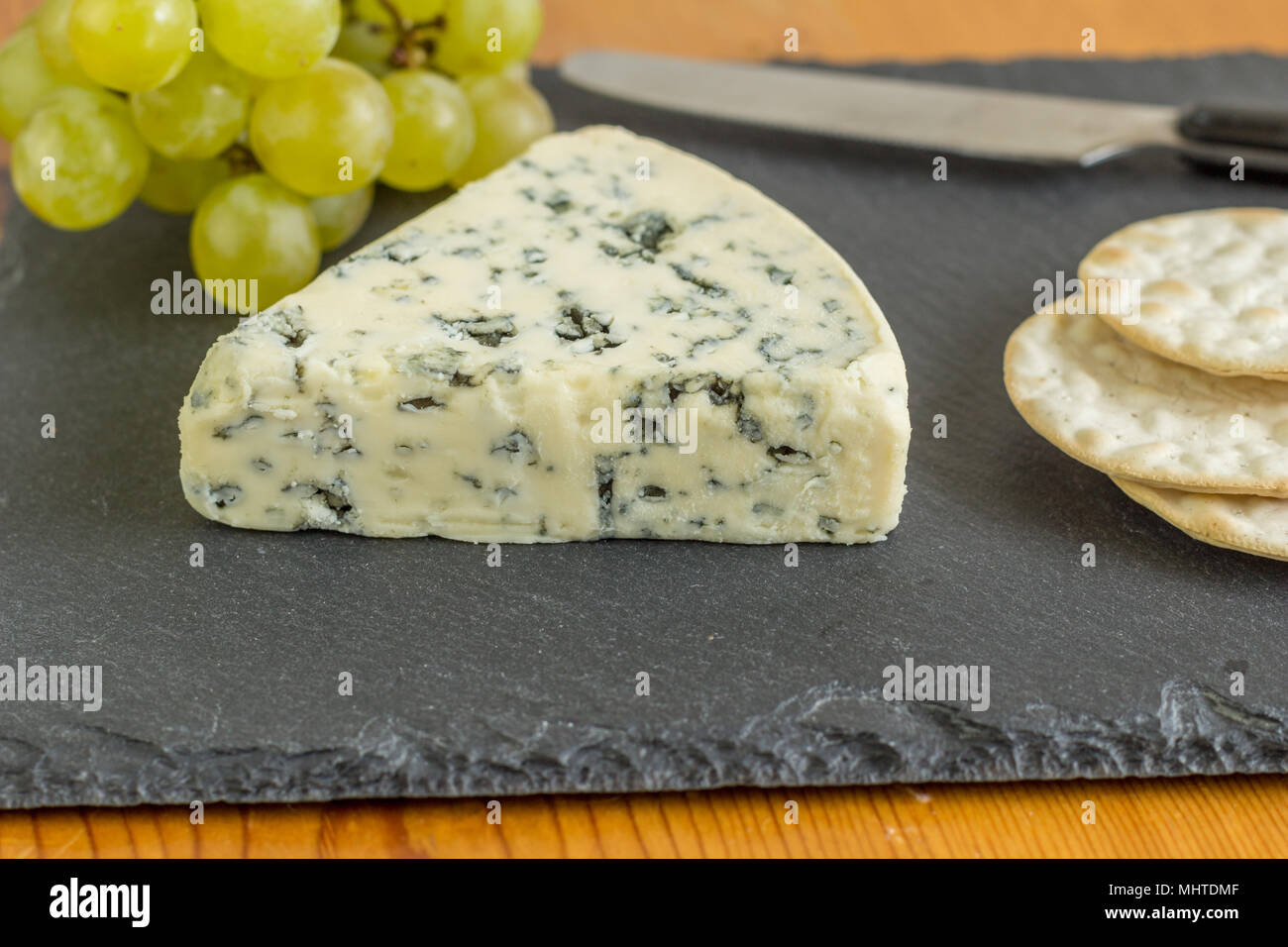 Stilton blue Schimmelkäse Keil schließen bis auf schwarzer Schiefer Käsebrett mit selektiven Fokus Stockfoto