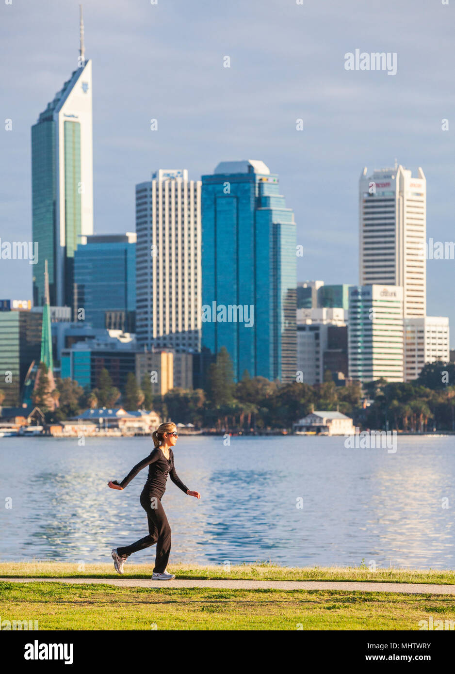 Eine Frau, die zu Fuß neben dem Swan River in Perth Perth City in der Ferne Stockfoto