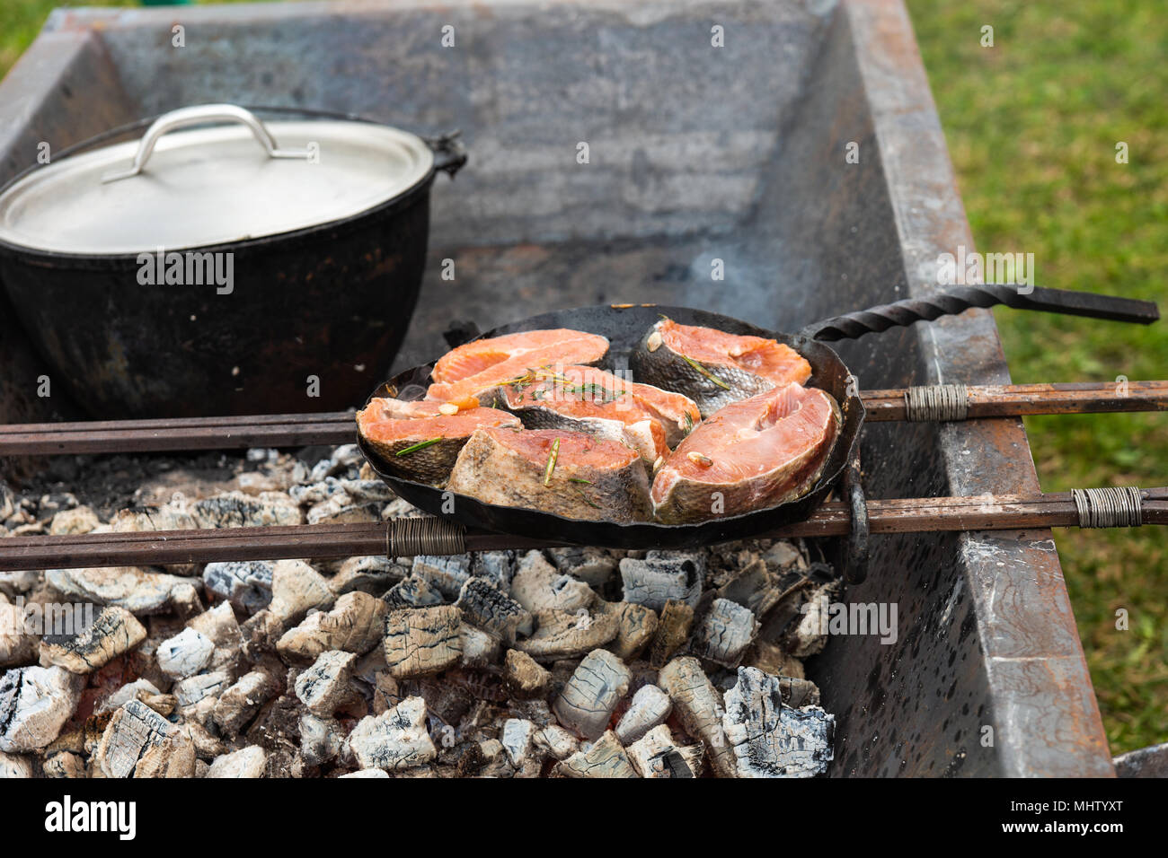 Stücke der roten Lachs Fisch Grill auf einer Pfanne, die auf Metall Stangen  über dem offenen Feuer Holzkohle Ofen steht. Zubereitung von Speisen in  einem mittelalterlichen Küche Stockfotografie - Alamy