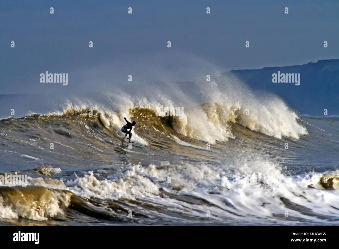 Ein einsamer Surfer reitet eine beeindruckende ankommenden Welle in der Scarborough South Bay. Stockfoto