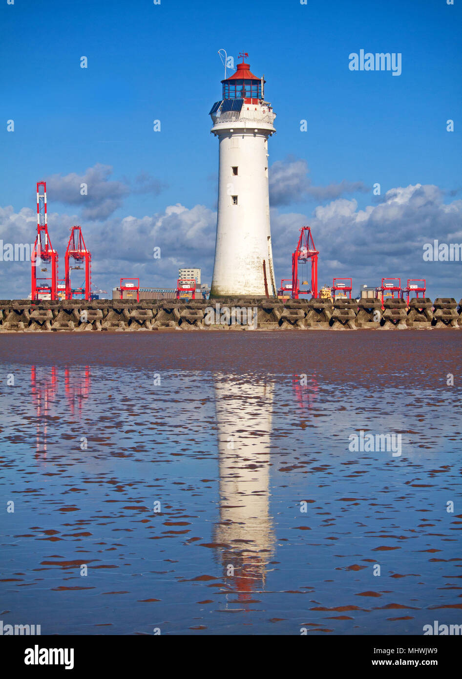 Ein Porträt von Barsch Rock Leuchtturm, über das Meer Verteidigung von New Brighton suchen, mit dem roten Krane von Liverpool Docks im Hintergrund Stockfoto