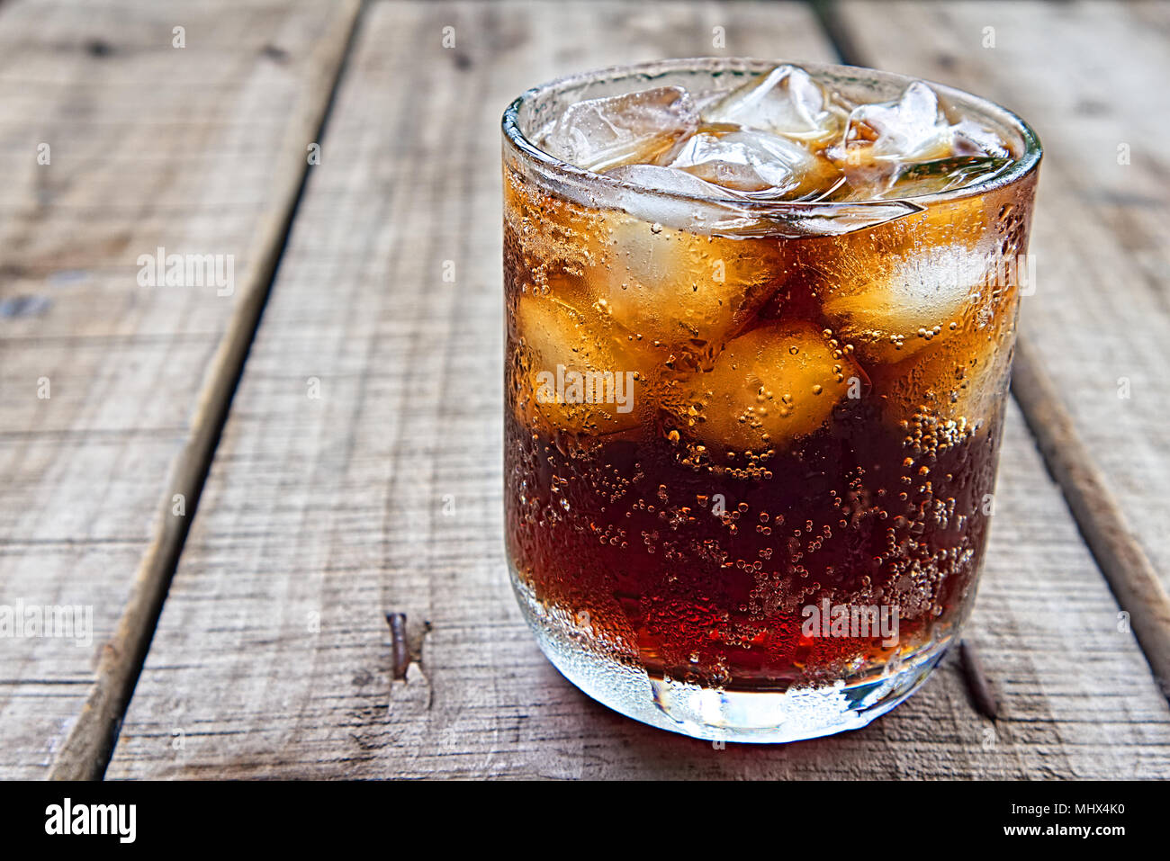 Ein Glas Coca Cola mit Eis auf Holz Platte Stockfoto