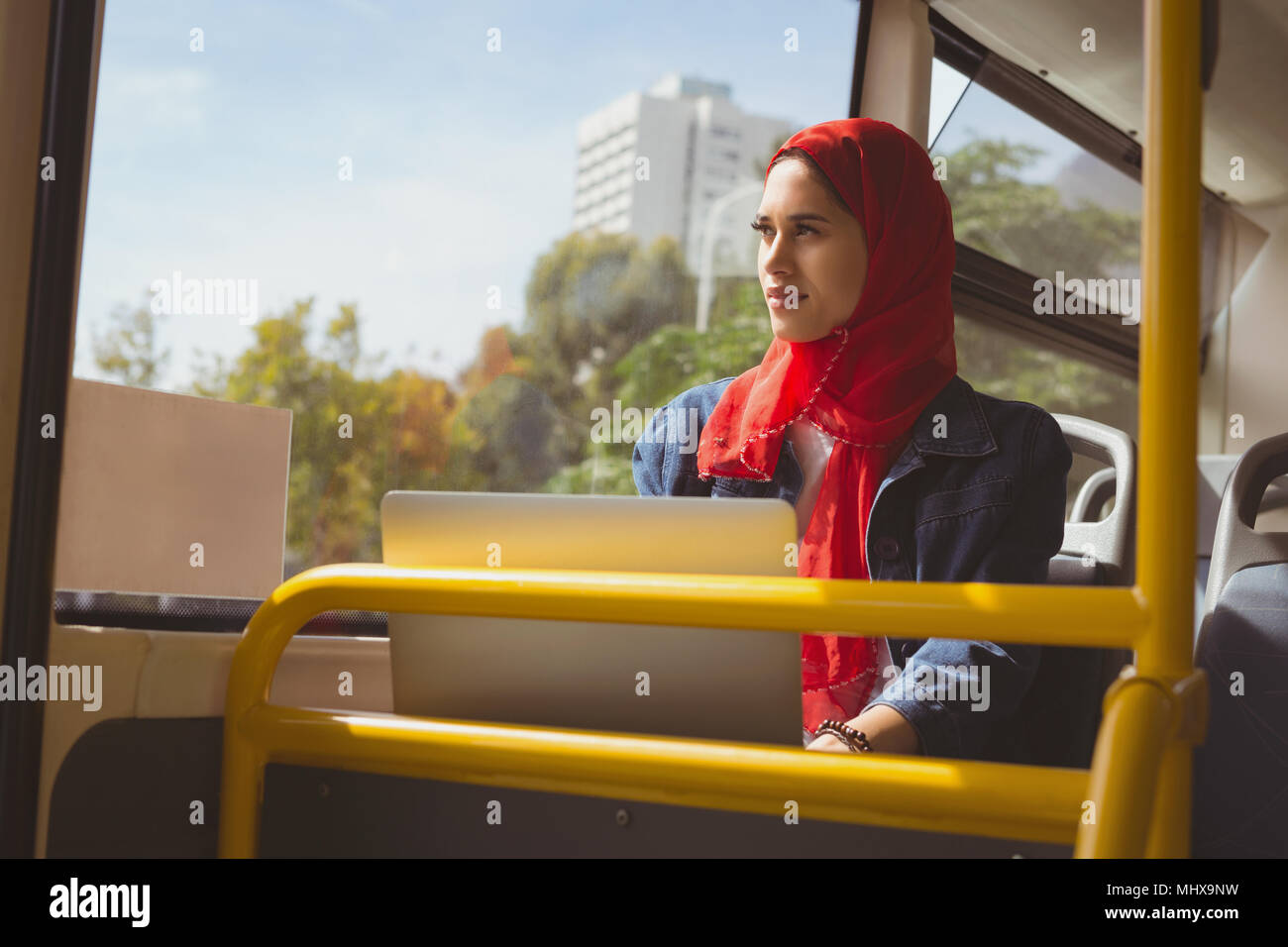 Hijab Frau mit Laptop auf der Suche durch das Fenster in den Bus Stockfoto