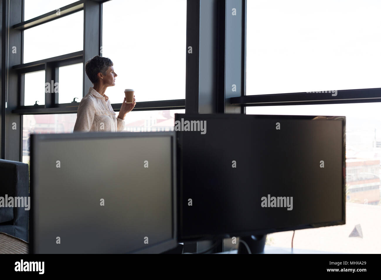 Reife Geschäftsfrau Blick durch Fenster, während Kaffee Stockfoto