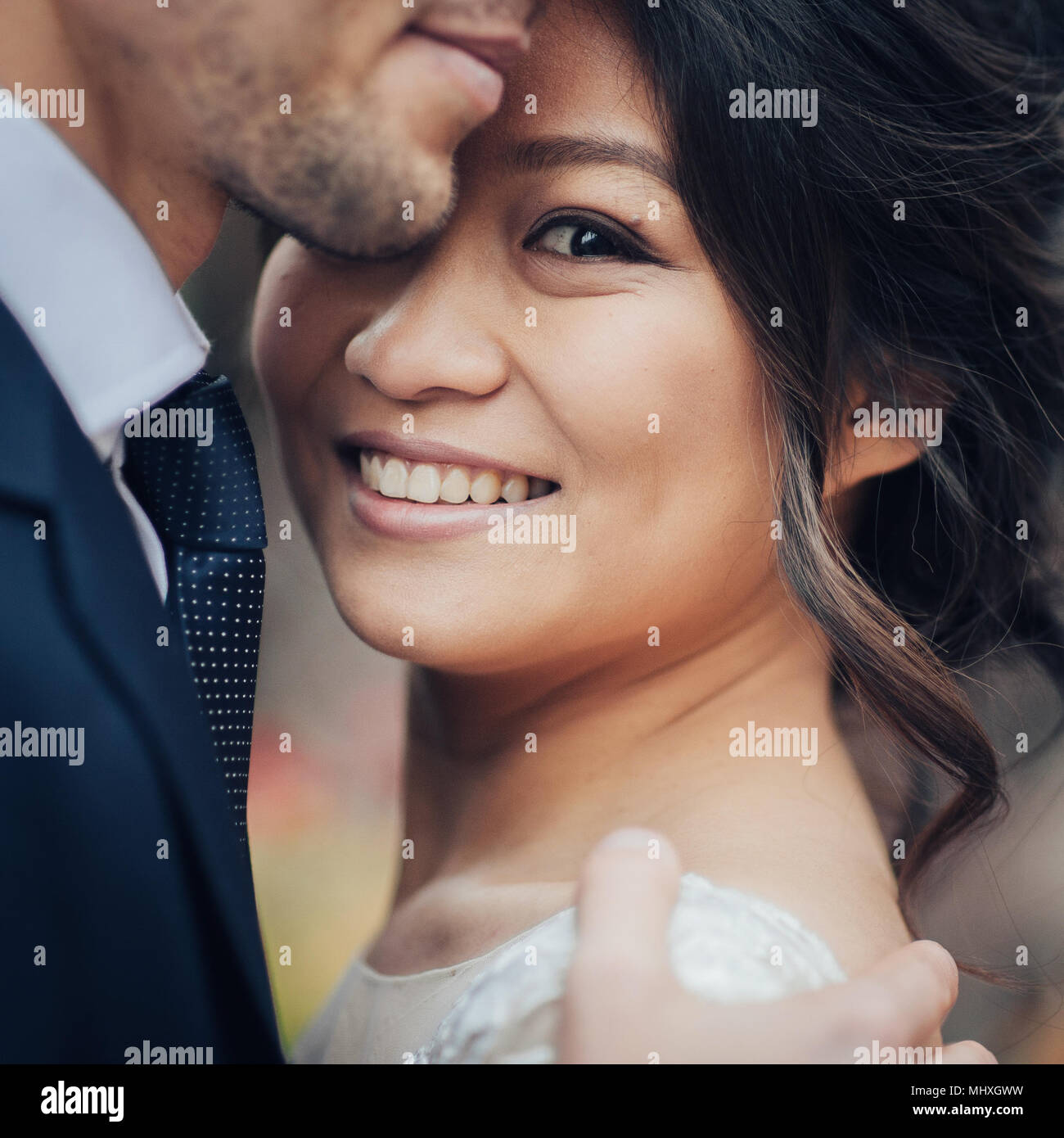 Bräutigam zärtlich umarmen asiatische Braut im weißen Kleid Stockfoto