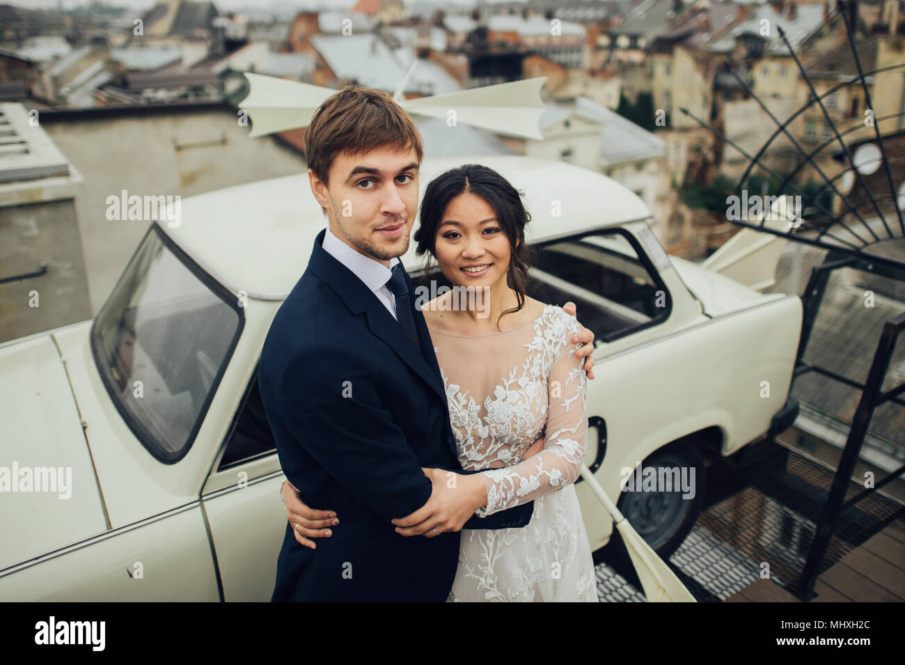Braut und Bräutigam auf dem Dach in der Nähe der Alten retro Auto mit Panoramablick auf die Stadt Stockfoto