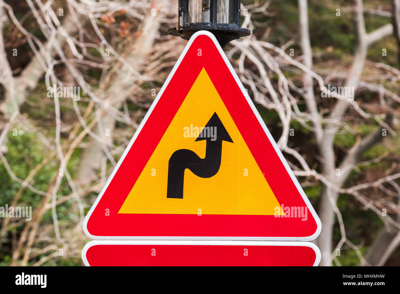 Gefährliche Kurven, Dreieck Warnung Verkehrsschild in der Nähe der Landstraße Stockfoto