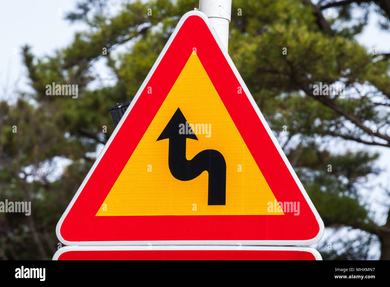 Gefährliche Kurven, gelbes Dreieck Warnung Verkehrsschild mit rotem Rahmen Stockfoto