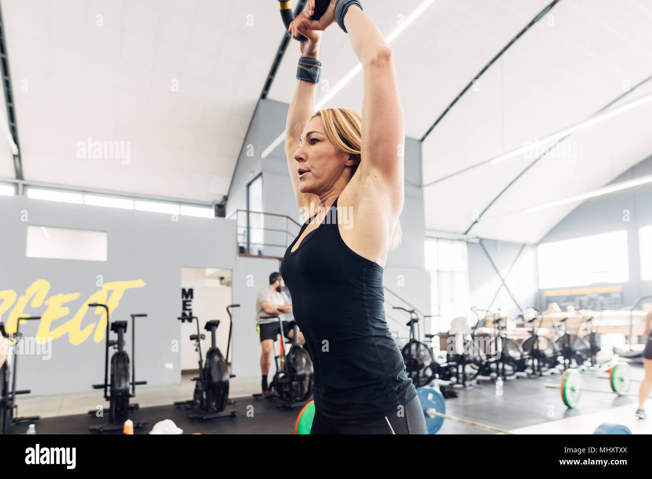 Frau Gewichtheben mit Wasserkocher Bell in der Turnhalle Stockfoto