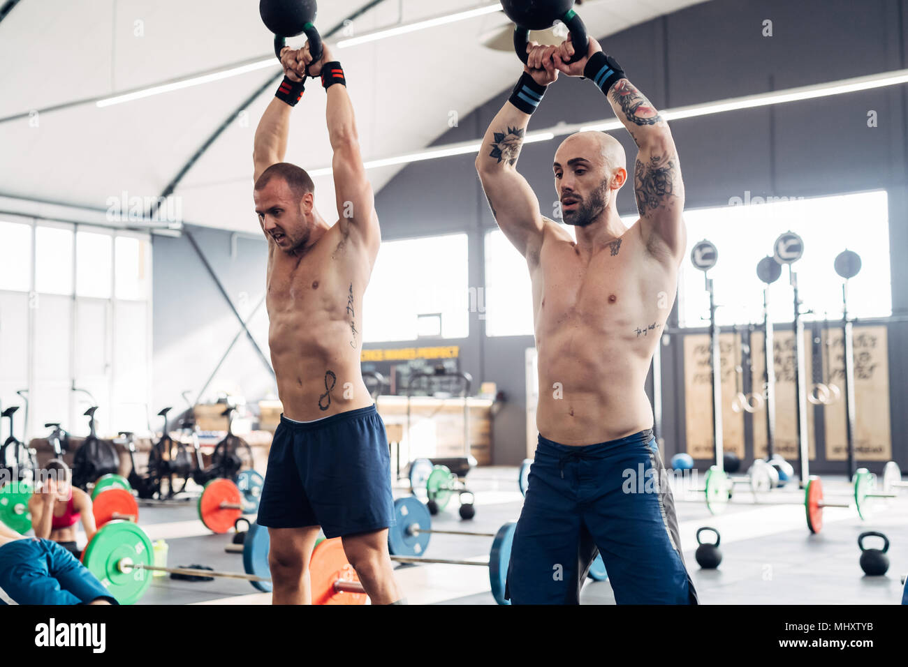 Männer Gewichtheben mit Wasserkocher Glocken in der Turnhalle Stockfoto