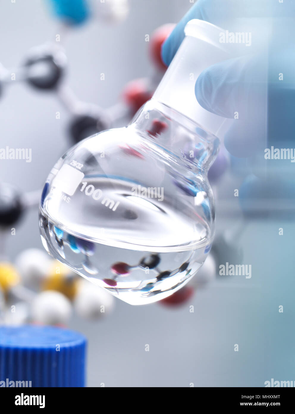 Wissenschaftler Vorbereitung chemische Formel in einem Labor Kolben während eines Experimentes, molekulare Modell im Hintergrund Stockfoto