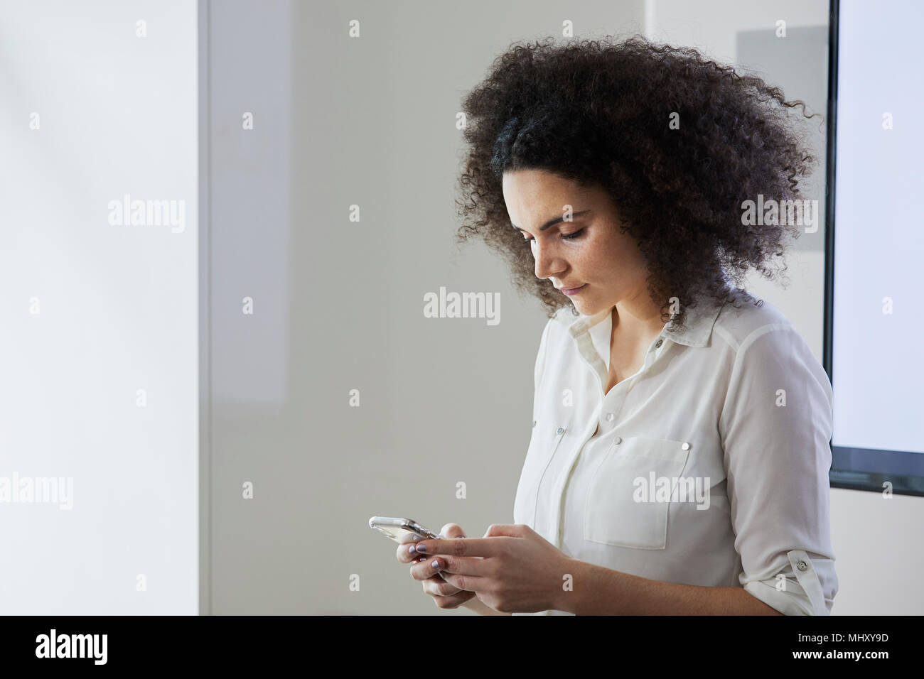 Im Büro von SMS-Nachrichten auf dem Smartphone Geschäftsfrau Stockfoto