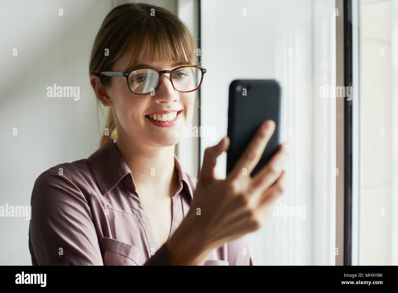 Frau lächelnd Smartphone betrachten Stockfoto
