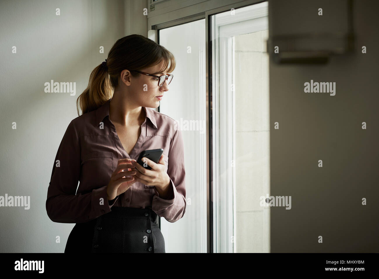 Geschäftsfrau Blick aus Fenster nachdenklich Stockfoto